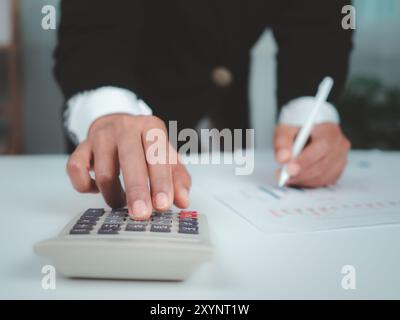 Businesswoman in black suit working on laptop computer and tablet and calculator, Hand Hands touch on tablet at office with dark background, Online wo Stock Photo