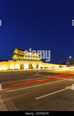 Long exposure car lights leaving trailing streak in front of Gwanghwamun main gate to historic Gyeongbokgung Palace at dusk in downtown on a clear nig Stock Photo