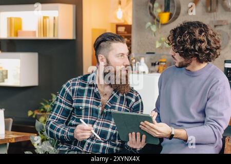 Two male designers are having a discussion about a project, using a digital tablet to review their work Stock Photo