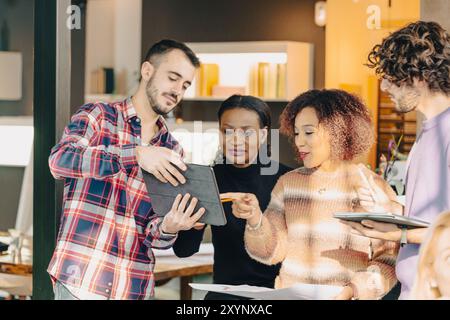 Four businesspeople having a productive meeting and using a digital tablet while working on a project in the office Stock Photo
