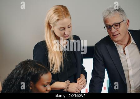 Business team having a discussion while analyzing data on a digital screen Stock Photo