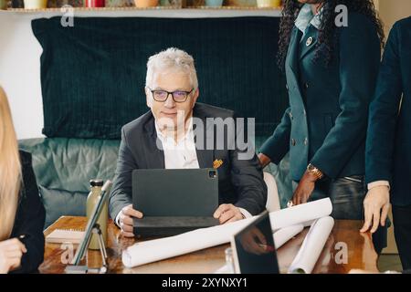 Team of business professionals are having a meeting in the office, discussing a project and using a digital tablet Stock Photo