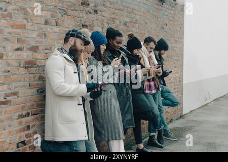 Group of young adults are ignoring each other, more interested in using their smartphones Stock Photo