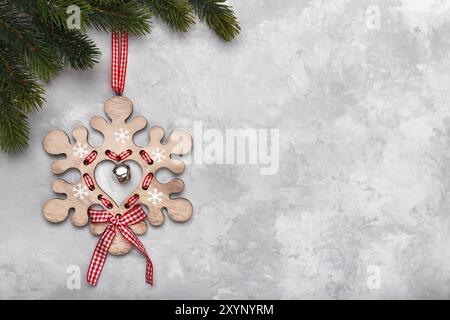 Christmas or new year background pine tree branch wooden snow flake decoration hanging on red ribbon gray background Stock Photo