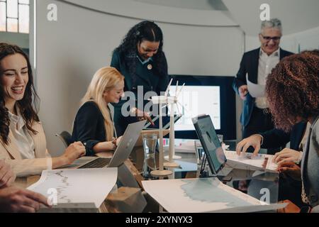 Diverse team of businesspeople are having a meeting about renewable energy, smiling and looking happy Stock Photo