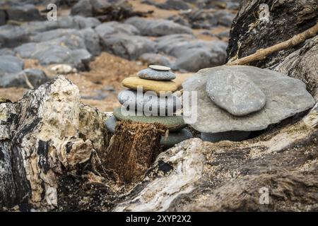 A stone pile on a tree trunk, with the background of Cocklawburn Beach near Berwick-upon-Tweed in Northumberland, England, UK Stock Photo