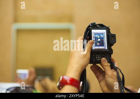 The famous Mona Lisa painting displayed in the back of a camera lcd screen at the Louvre in Paris, France, Europe Stock Photo