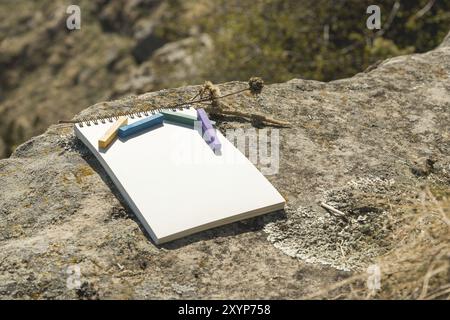 Close-up artwork for the designer. A blank notepad for drawing pastel on which lay an artistic pastel crayons color chalks of purple green blue and ye Stock Photo