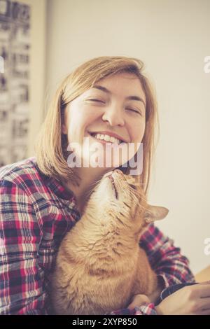 Red tabby cat is kissing a young beautiful girl, closeup Stock Photo