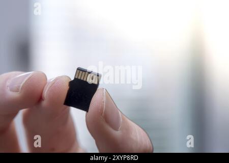 Young man is holding a tiny memory card in his hand, text space Stock Photo