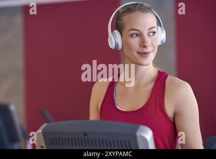 Smiling young blond woman wearing headphone in gym Stock Photo
