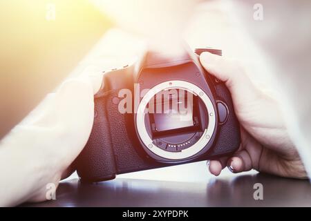 Hands of a photographer are touching a professional reflex camera, open sensor. Sunlight Stock Photo