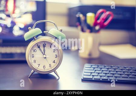 Alarm clock on the desk, office stuff in the blurry background, deadlines and todos Stock Photo
