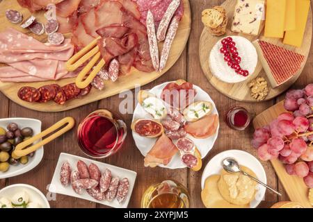 Charcuterie Tasting. A photo of many different sausages and hams, deli meats, and a cheese platter, shot from above on a rustic background with a glas Stock Photo