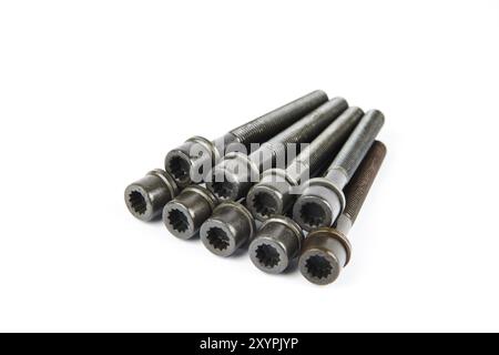 A set of new cylinder head bolts in oil on a white isolated background are shot in perspective at a wide angle. Spare parts for car repair Stock Photo