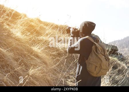 Woman hipster-photographer with dslr camera take pictures, Stylish girl in sunglasses with a camera on the nature Stock Photo