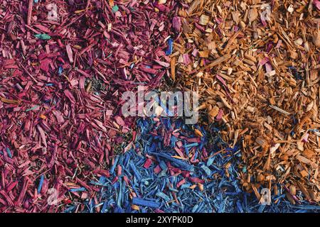 Textured background decorative colored sawdust for finishing flower beds in the winter season. Yellow red and blue sawdust Stock Photo
