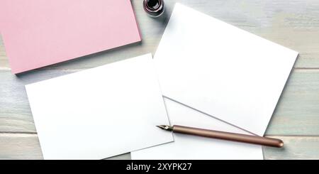 Stationery mock-up with an ink bottle and a nib pen. Blank greeting cards or invitations, overhead panoramic shot Stock Photo