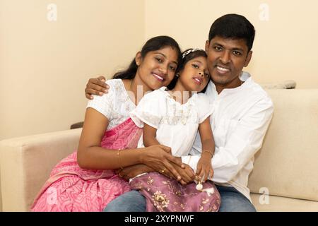 A family sits closely together on a couch, smiling and laughing Stock Photo