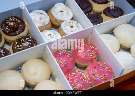 A delicious box selection of colourful doughnuts, including pink and chocolate ones with sprinkles Stock Photo