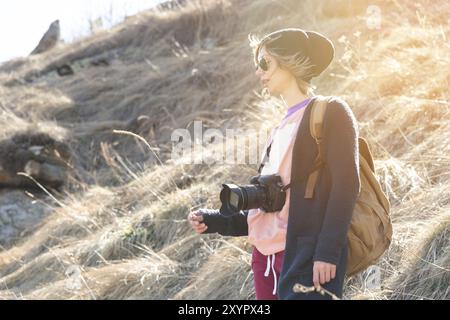 Woman hipster-photographer with dslr camera. Stylish girl in sunglasses with a camera on the nature Stock Photo