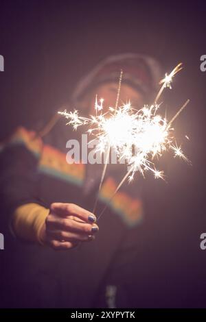 Smiling girl is holding a sparkler in her hand, new year, outdoors Stock Photo