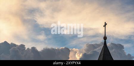 Roof tower of church with cross on the top against sky orange and blue colors. Sky abstract background. religion concept Stock Photo