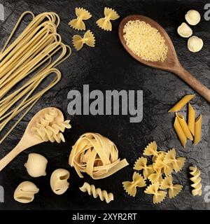 An overhead photo of different types of pasta, including spaghetti, penne, fusilli, and others, shot from above on a black background with a place for Stock Photo