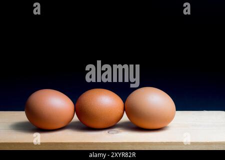 still life of three eggs on table against black background Stock Photo