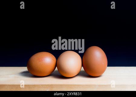 three eggs disposed on table against black background Stock Photo