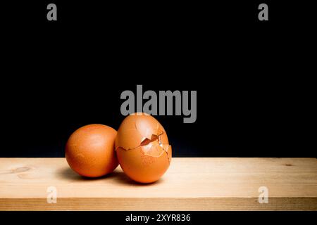 next egg to break - two eggs on table against black background Stock Photo