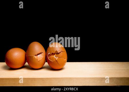 next egg to break - three eggs on table against black background Stock Photo