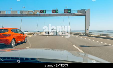 Lisbon, Portugal, August 3, 2024. Cars move steadily on a multi-lane bridge with electronic speed signs above. Stock Photo