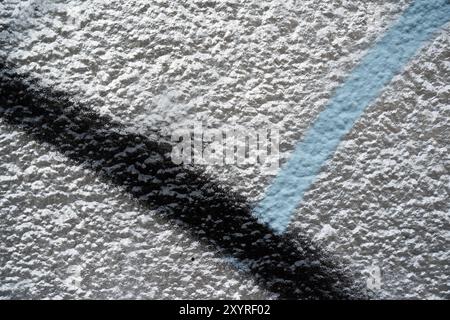 Detail of a plastered house wall sprayed with silver paint and black stripes and light blue stiff Stock Photo