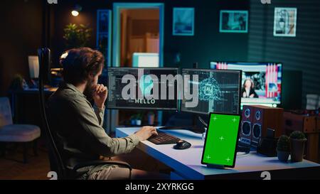 Focus on isolated screen tablet next to programmer updating artificial intelligence, making it become sentient. IT specialist programming self aware AI with chroma key device, camera B Stock Photo