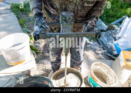 The Master At The Construction Site Mixes Glue With Water Preparing