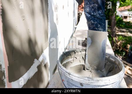 Installation of reinforcing mesh on a facade. Repair of the facade of the house, plastering of walls from expanded polystyrene using special glue and Stock Photo