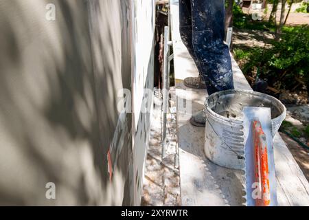 Installation of reinforcing mesh on a facade. Repair of the facade of the house, plastering of walls from expanded polystyrene using special glue and Stock Photo