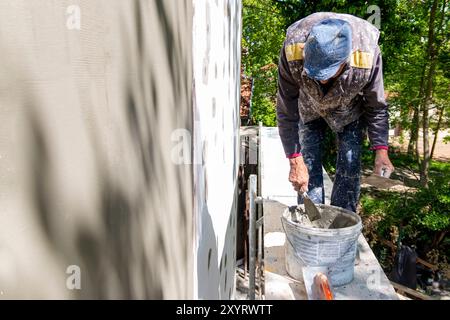 Installation of reinforcing mesh on a facade. Repair of the facade of the house, plastering of walls from expanded polystyrene using special glue and Stock Photo