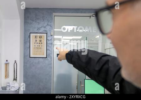 Senior man choosing eyeglasses and doing the eyesight test at optician clinic. Stock Photo