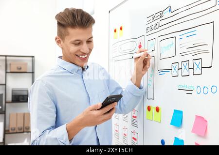 Developing UI design. Man drawing website wireframe on whiteboard indoors Stock Photo