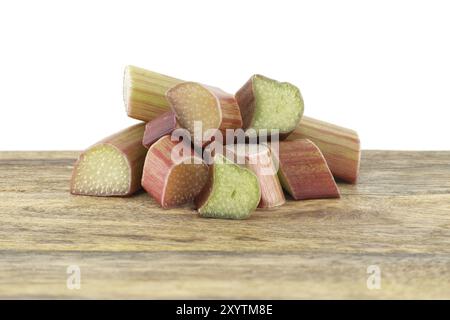 Variety of rhubarb stalks of varying colors from pale green to deep red on wooden cutting board isolated on white background Stock Photo