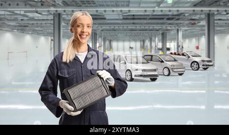 Female car mechanic holding air filter in a car garage Stock Photo