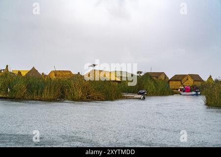 Soft focus view of Uros floating island on Titicaca Lake in the rain with the houses made of totora reeds and Uros women wearing in beautiful traditio Stock Photo