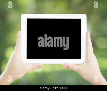 Man hands holding tablet PC against spring green background Stock Photo