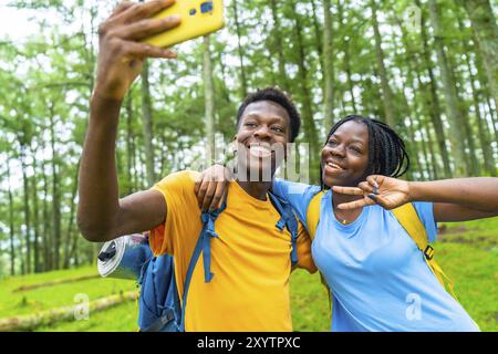 Happy young african friends gesturing success while taking selfie together in a green forest Stock Photo