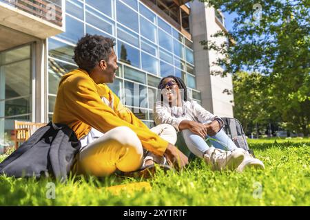 Happy african students sitting on ground in the campus chatting and having fun together Stock Photo