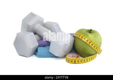 Health and fitness equipment including two gray dumbbells, green apple with a tape measure wrapped around it isolated on white background Stock Photo