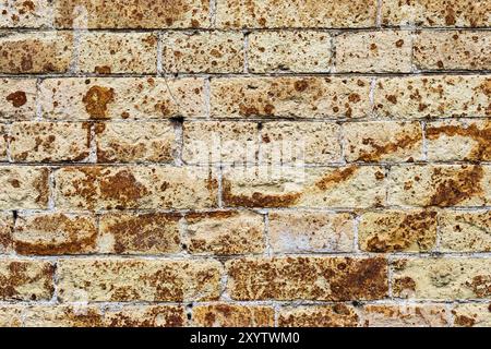 Background wall from an ancient yellow vintage brick with rusty corrosion patterns on the surface. Textured background in grunge style. Procurement fo Stock Photo