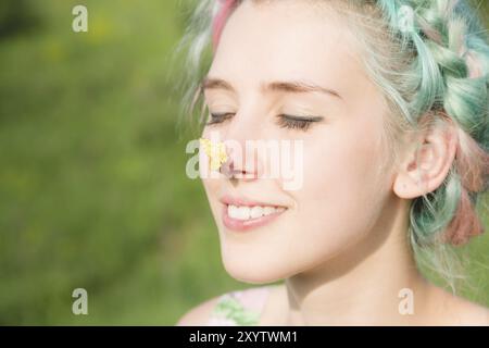 Yellow butterfly sitting on the nose Cute young girl on nature. Harmony and enjoyment in nature Stock Photo